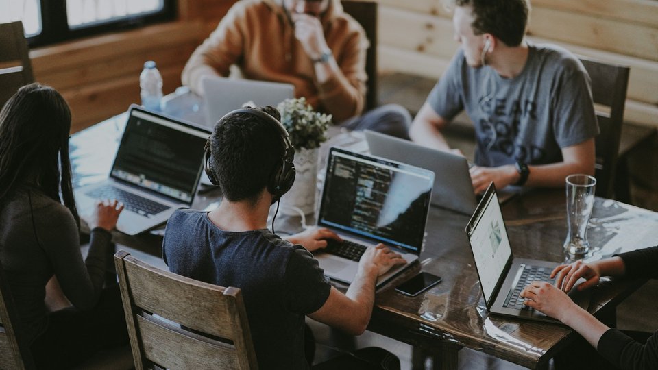 Colleagues collaborating over laptops in an open office